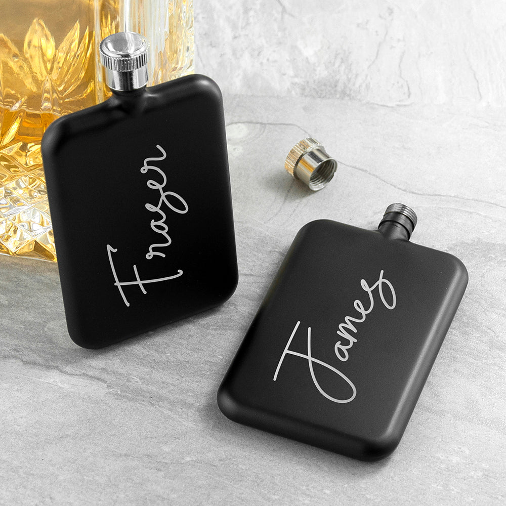 Two black flasks with 'Fraser' and 'James' engraved on them, placed on a light gray surface.