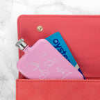 Pink hand warmer with 'Oystercard' design inside a pink wallet on a marble background