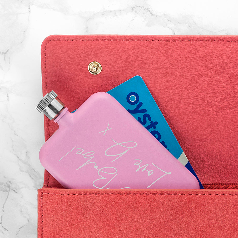 Pink hand warmer with 'Oystercard' design inside a pink wallet on a marble background
