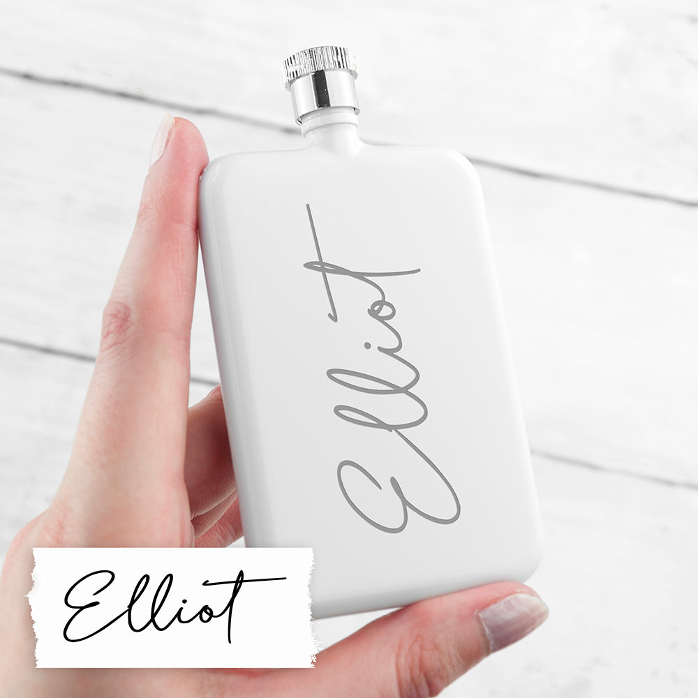 White flask with 'Elliot' branding held by a hand on a light background