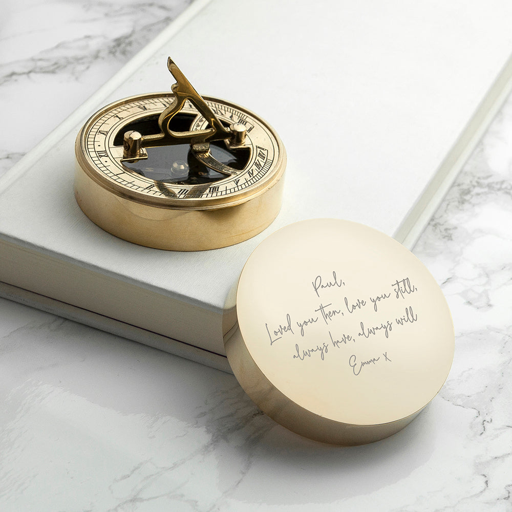 Gold compass with engraved lid on a marble surface