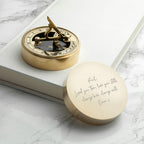 Gold compass with engraved lid on a marble surface