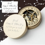 Gold compass with engraved message on a white surface