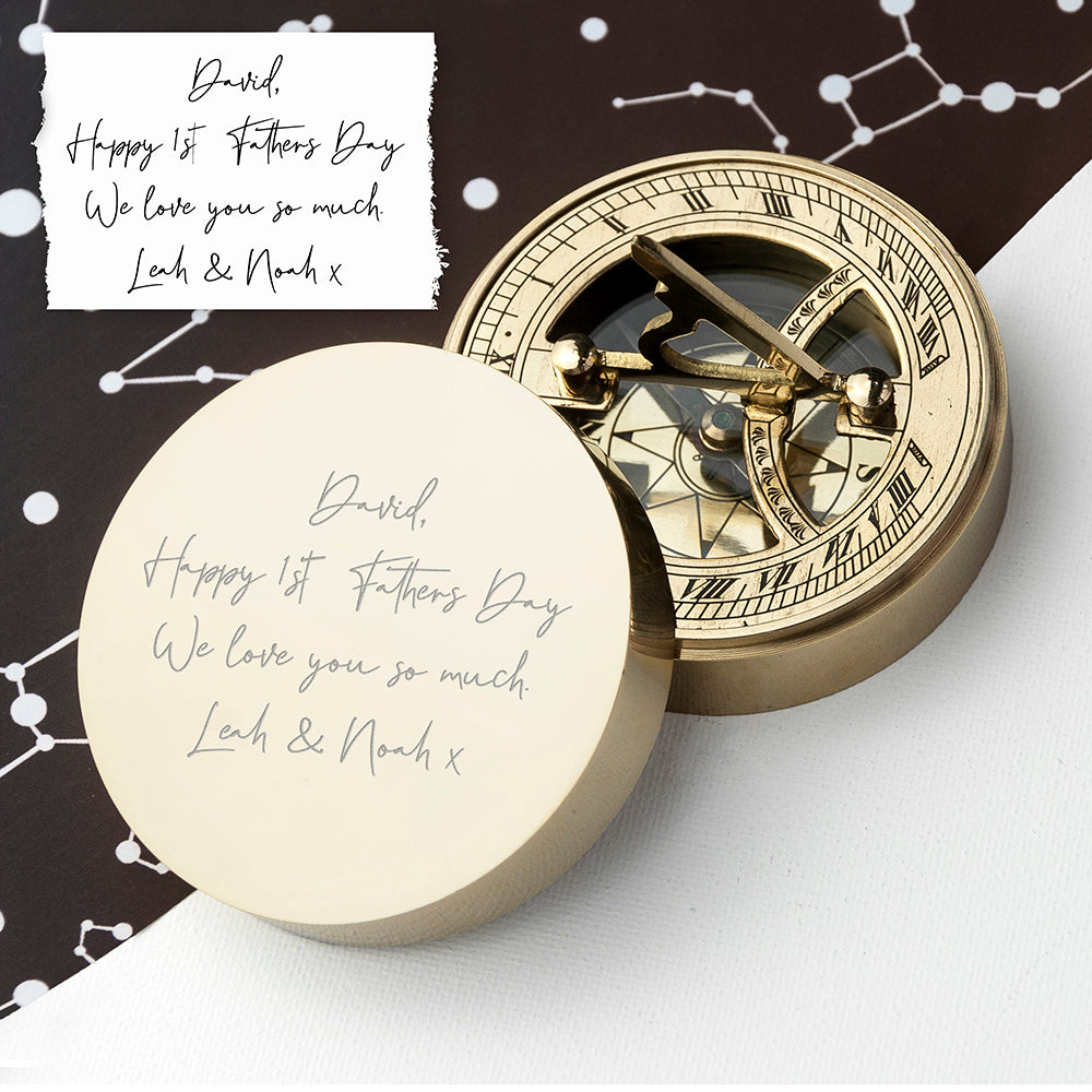 Gold compass with engraved message on a white surface