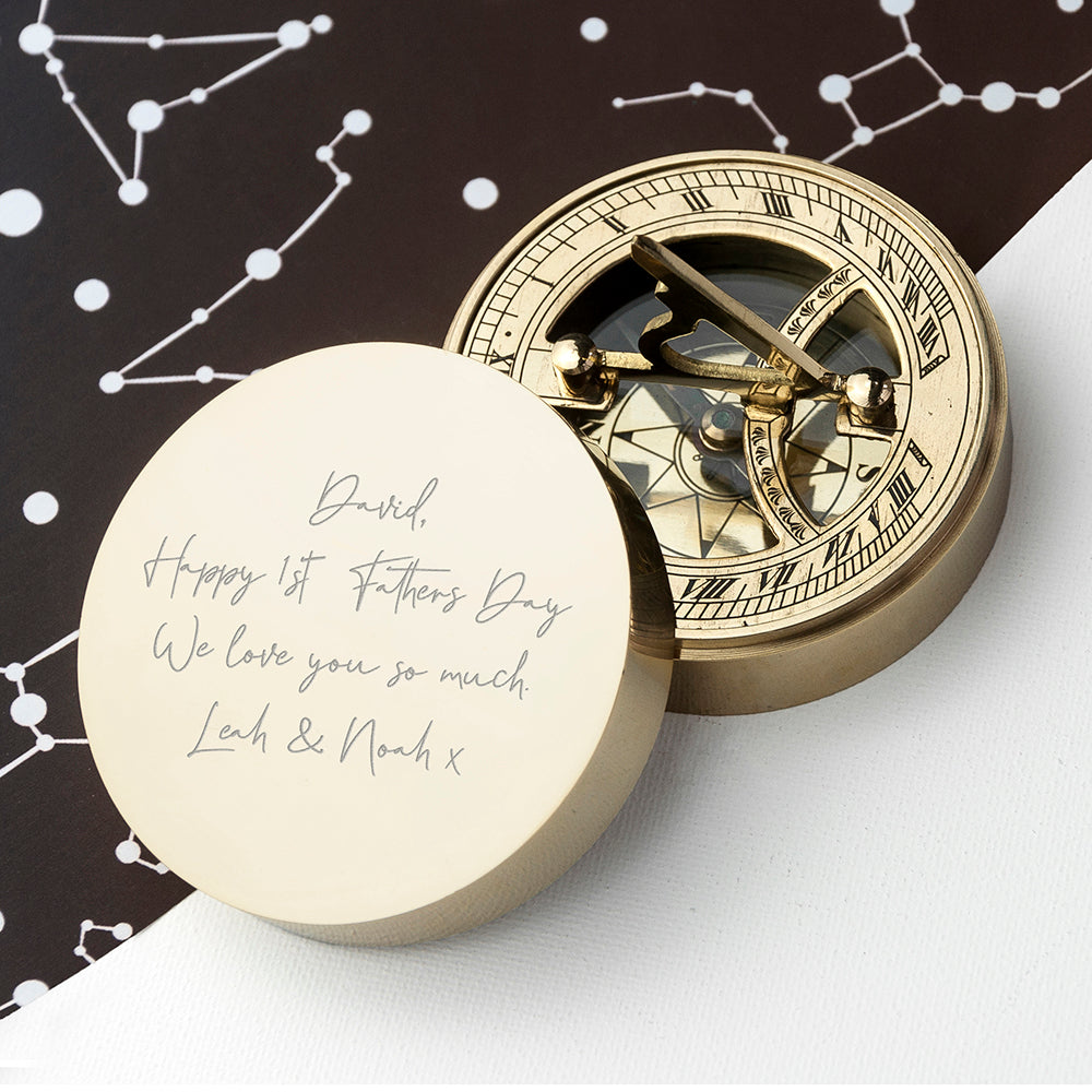 Gold compass with engraved message on a white surface