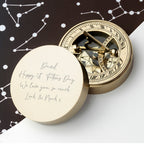 Gold compass with engraved message on a white surface