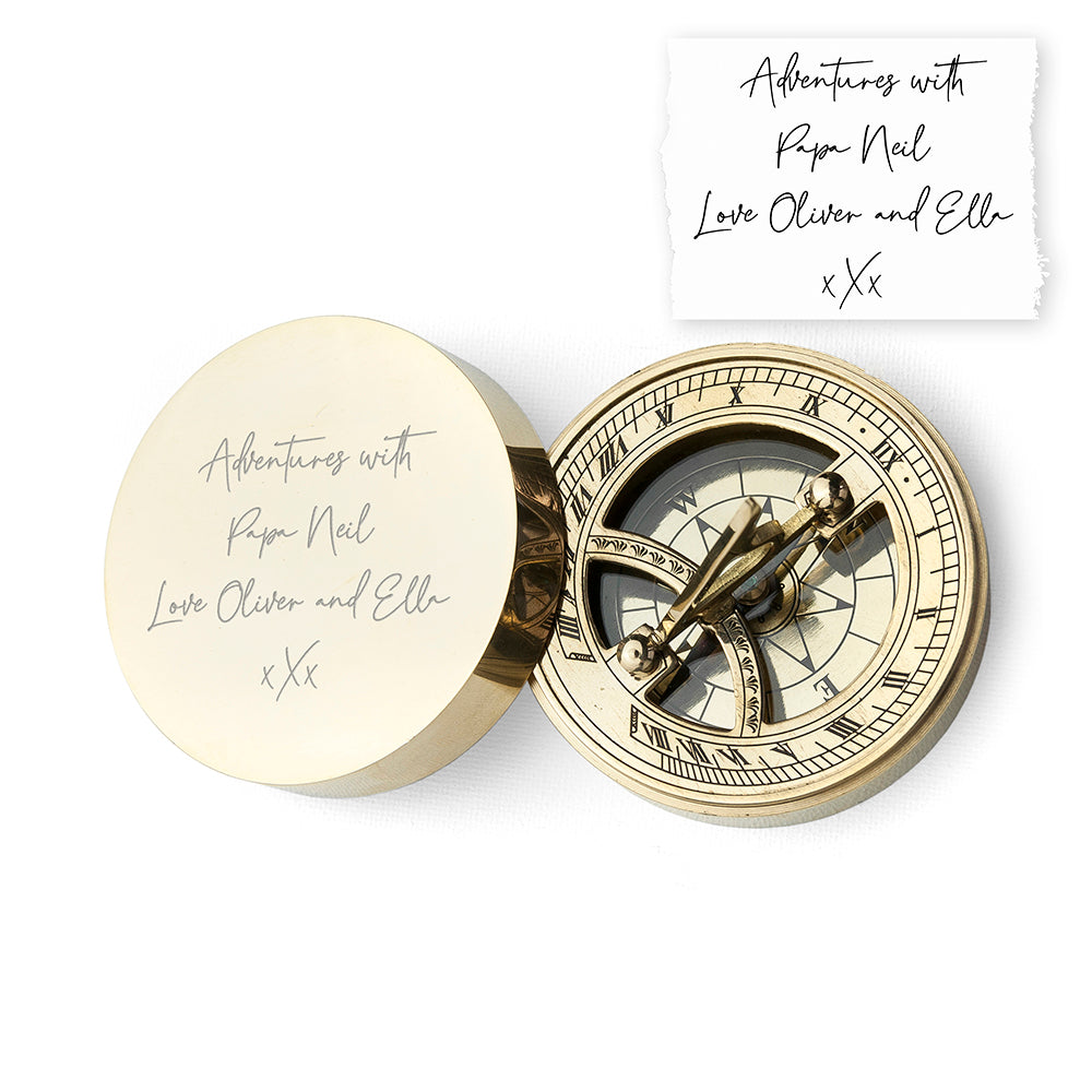 Brass compass with engraved text on a white background