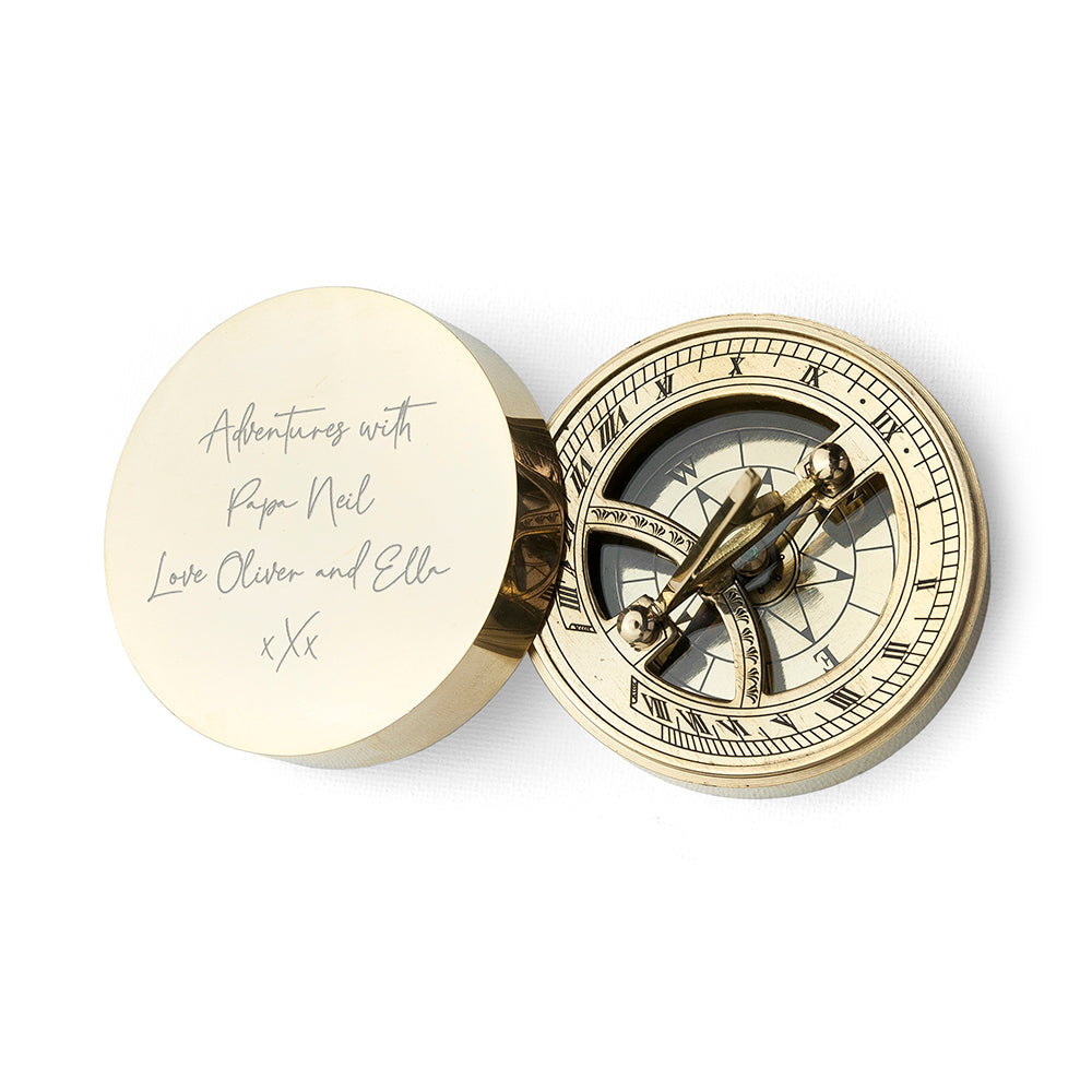 Brass compass with engraved lid on a white background