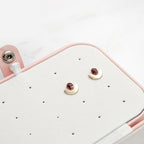 Pair of earrings on a white earring display with a pink holder.
