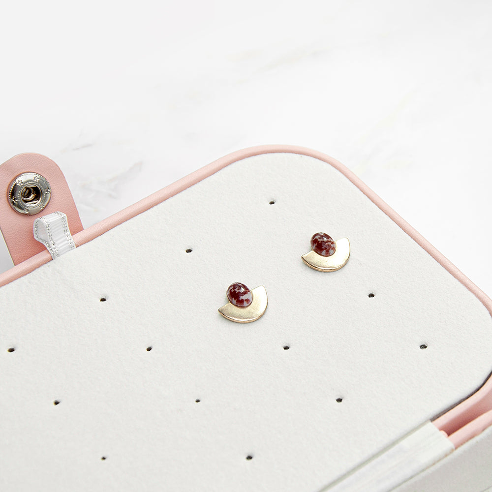 Pair of earrings on a white earring display with a pink holder.