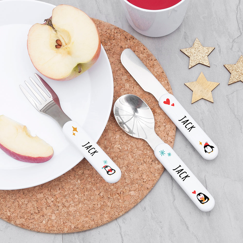 Children's cutlery set with 'JACK' on a plate with apple slices and a cup.