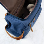 Blue toiletry bag with brown leather accents on a white background