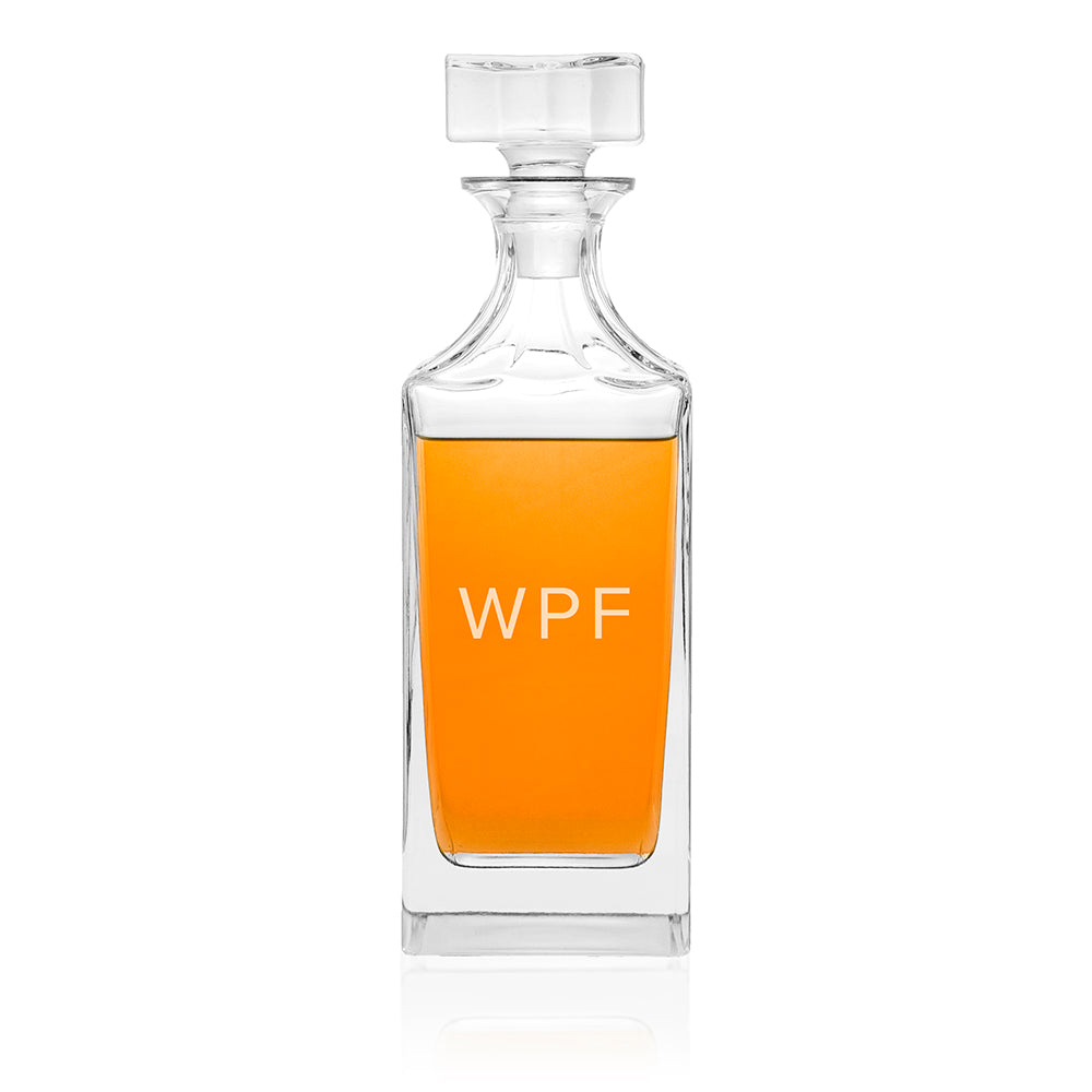Clear glass decanter with orange liquid and 'WPF' initials on a white background