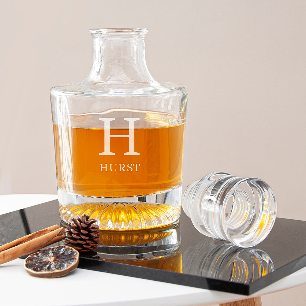 Glass whiskey decanter with 'HURST' branding on a reflective surface.