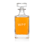 Clear glass decanter with orange liquid and 'WPF' branding on a white background
