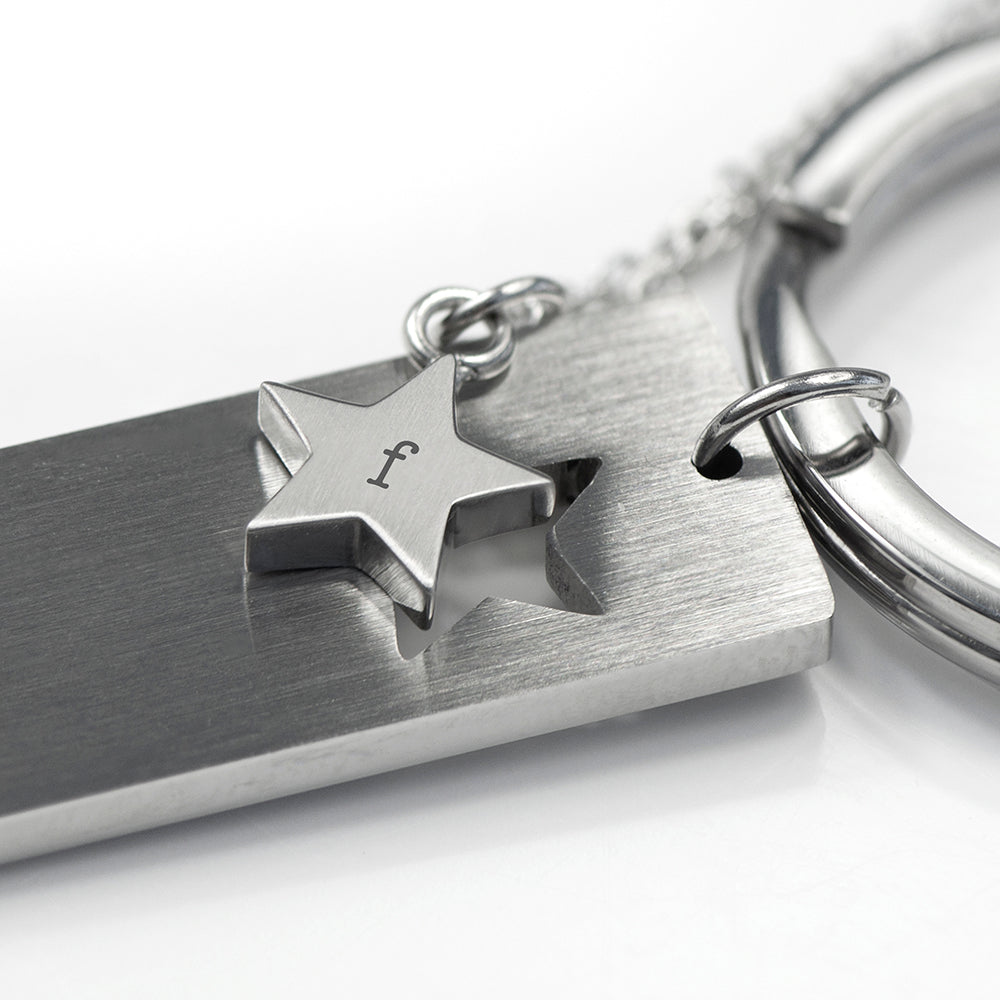 Silver keychain with star-shaped tag and engraved letter 'f' on a white background