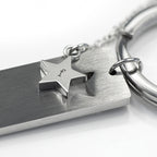 Silver keychain with star-shaped tag and engraved letter 'f' on a white background