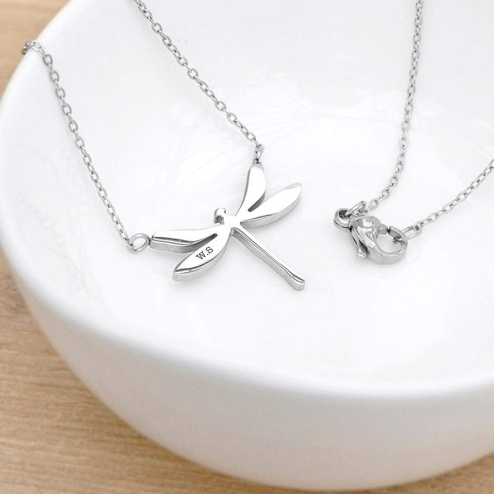 Silver dragonfly necklace on a white dish