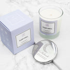 Candle labeled 'Sleep Well' with packaging and a mirror on a marble surface