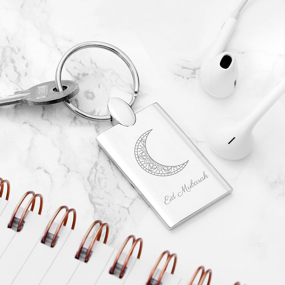 Keychain with geometric crescent moon design and 'Ed Mubarak' text on a marble surface.