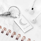 Keychain with geometric crescent moon design and 'Ed Mubarak' text on a marble surface.