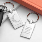 Silver keychains with engraved text and designs on a white surface