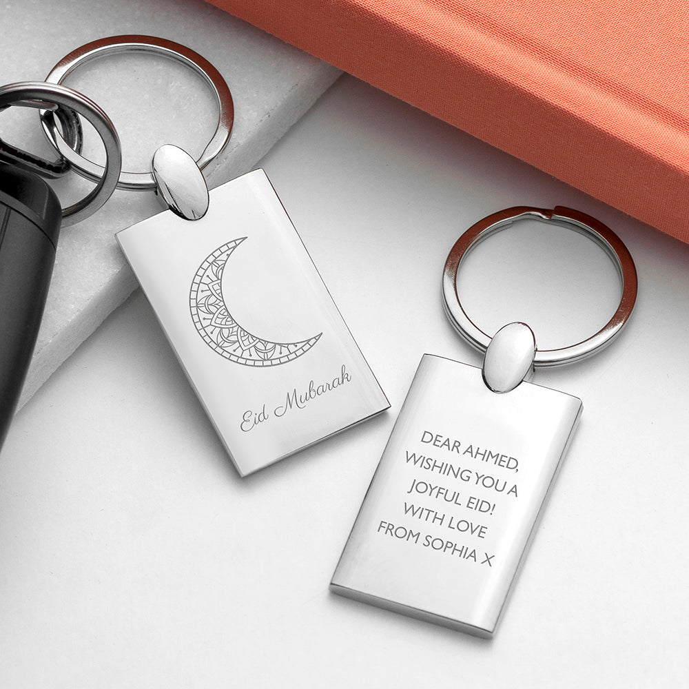 Silver keychains with engraved text and designs on a white surface