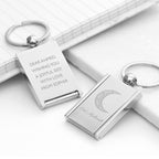 Silver keychains with engraved messages on a white surface