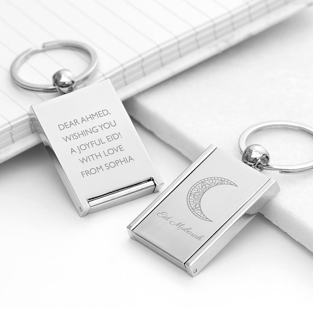 Silver keychains with engraved messages on a white surface