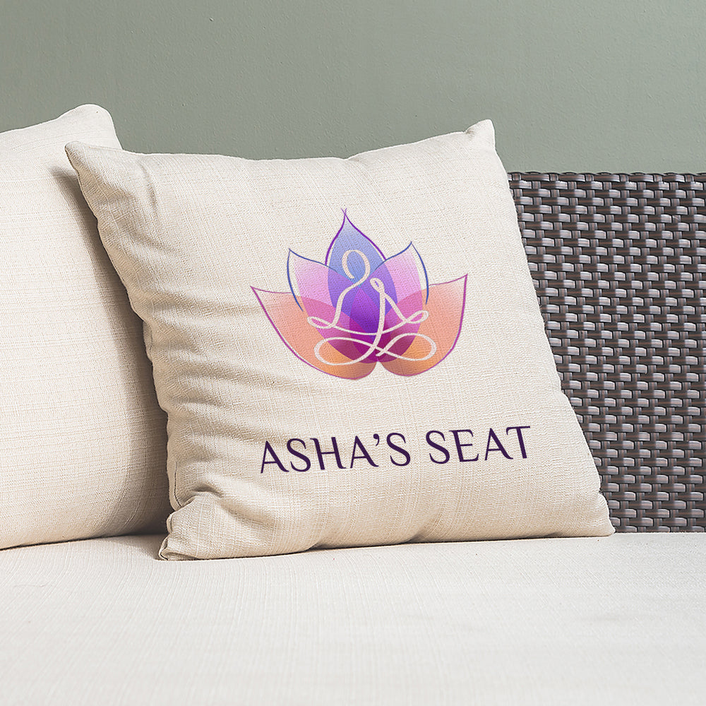 Beige pillow with 'Asha's Seat' logo on a gray couch