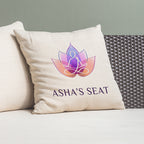 Beige pillow with 'Asha's Seat' logo on a gray couch