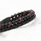 Black braided leather bracelet with red and black beaded design on a white background
