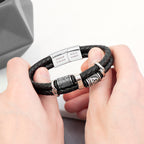 Black braided leather bracelet with silver metal clasp held by hands on a light background