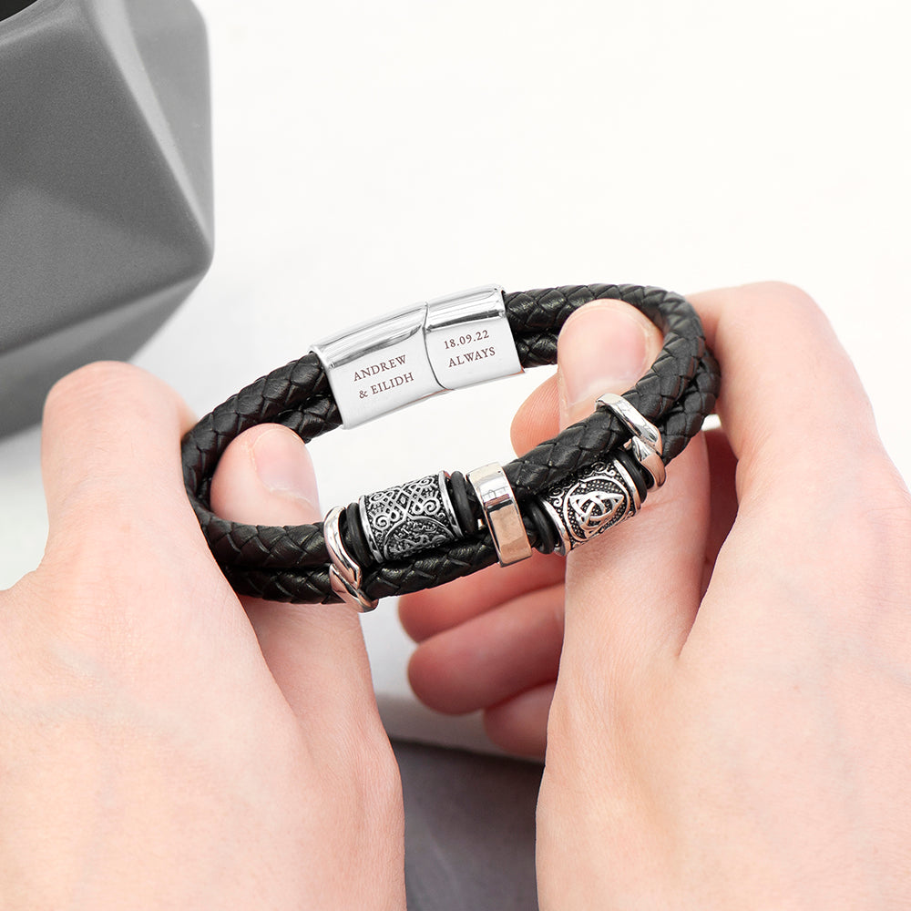 Black braided leather bracelet with silver metal clasp held by hands on a light background
