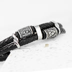 Black leather bracelet with silver metal beads on a light gray background