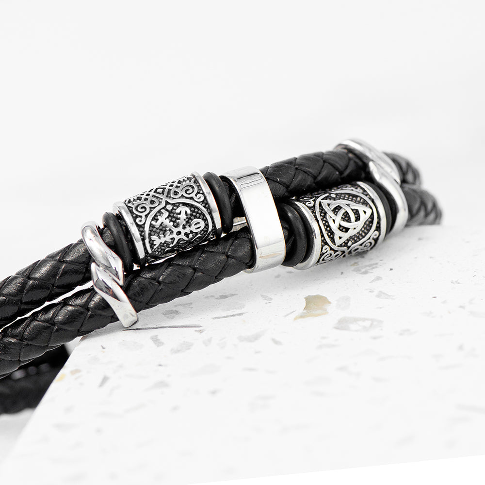 Black leather bracelet with silver metal beads on a light gray background