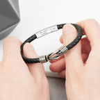 Black braided leather bracelet with silver clasp held by hands against a neutral background