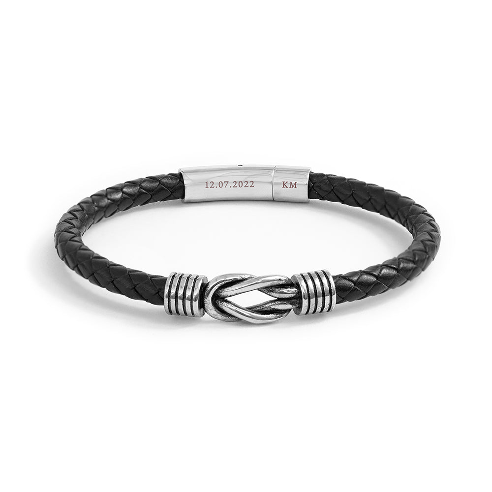 Black braided leather bracelet with silver clasp and engraved tag on a white background