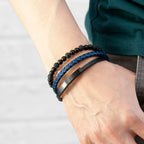 Close-up of a wrist wearing three bracelets on a plain background
