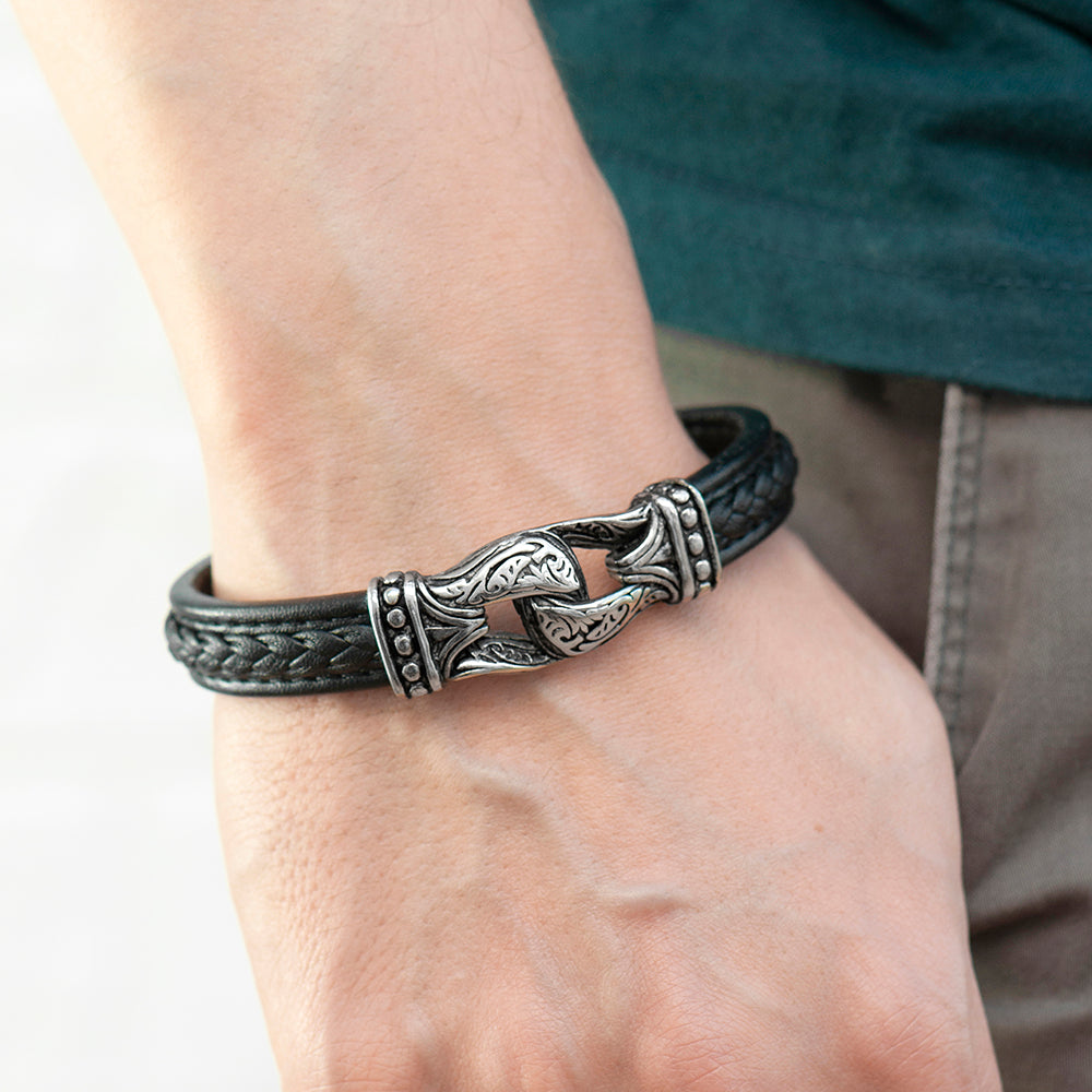 Black leather bracelet with silver intricate design on a wrist