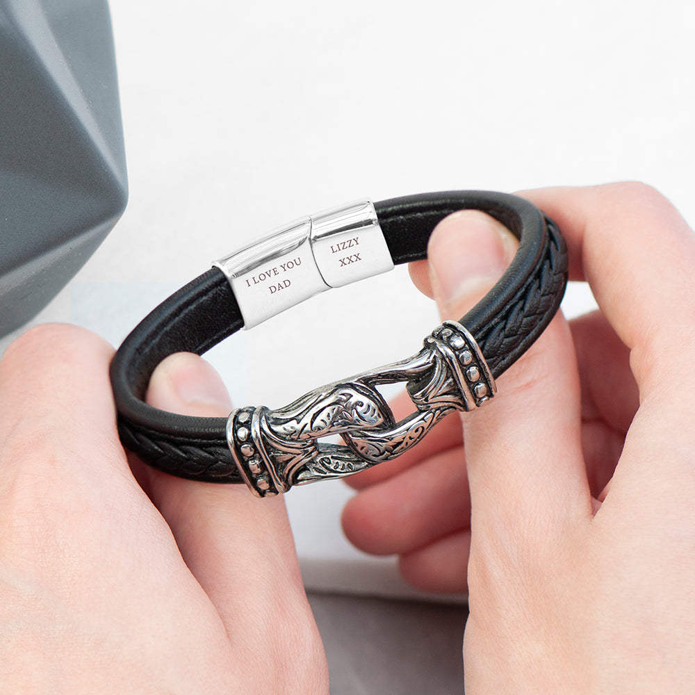 Black leather bracelet with silver clasp held by hands on a light background