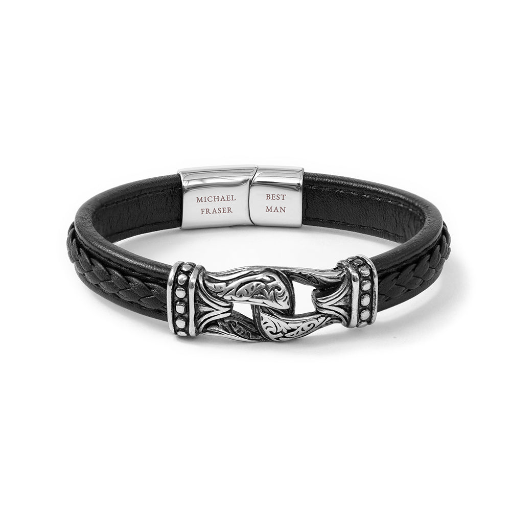 Black leather bracelet with silver clasp and engraved tag on a white background
