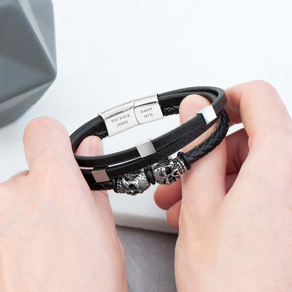 Black leather bracelet with silver beads held by hands on a light gray background
