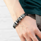 Bracelet with black leather strap and silver metal elements on a wrist against a white background
