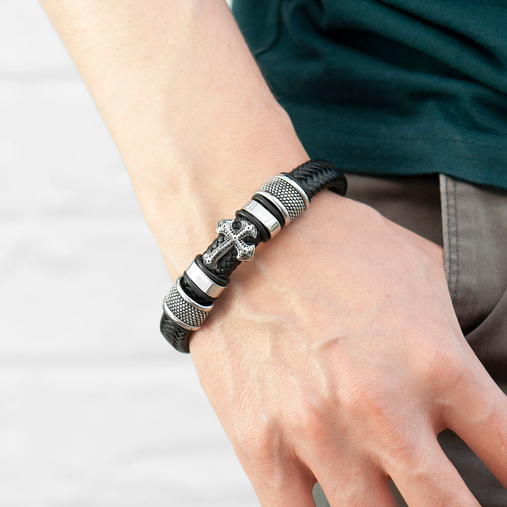 Bracelet with black leather strap and silver metal elements on a wrist against a white background