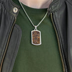 Person wearing a green shirt and black leather jacket with a necklace featuring a rectangular pendant.