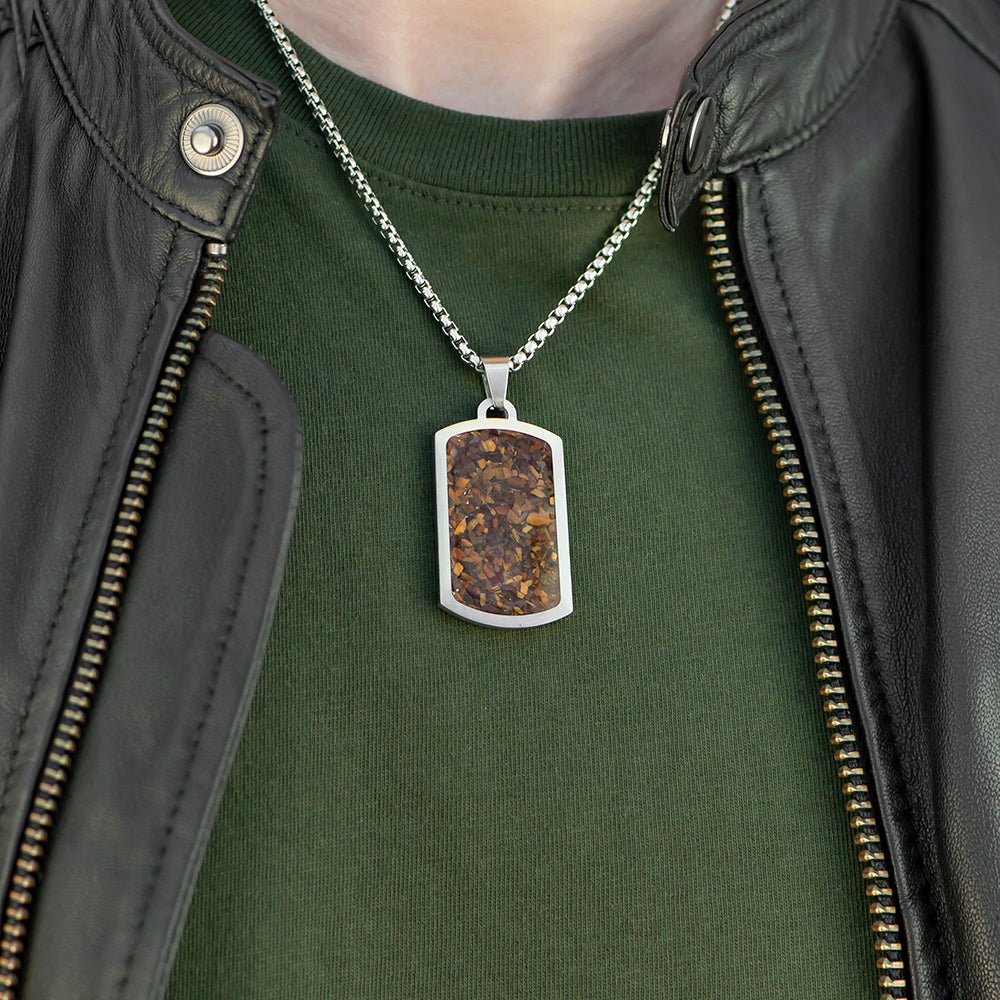 Person wearing a green shirt and black leather jacket with a necklace featuring a rectangular pendant.