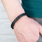 Black braided bracelet on a wrist with a neutral background