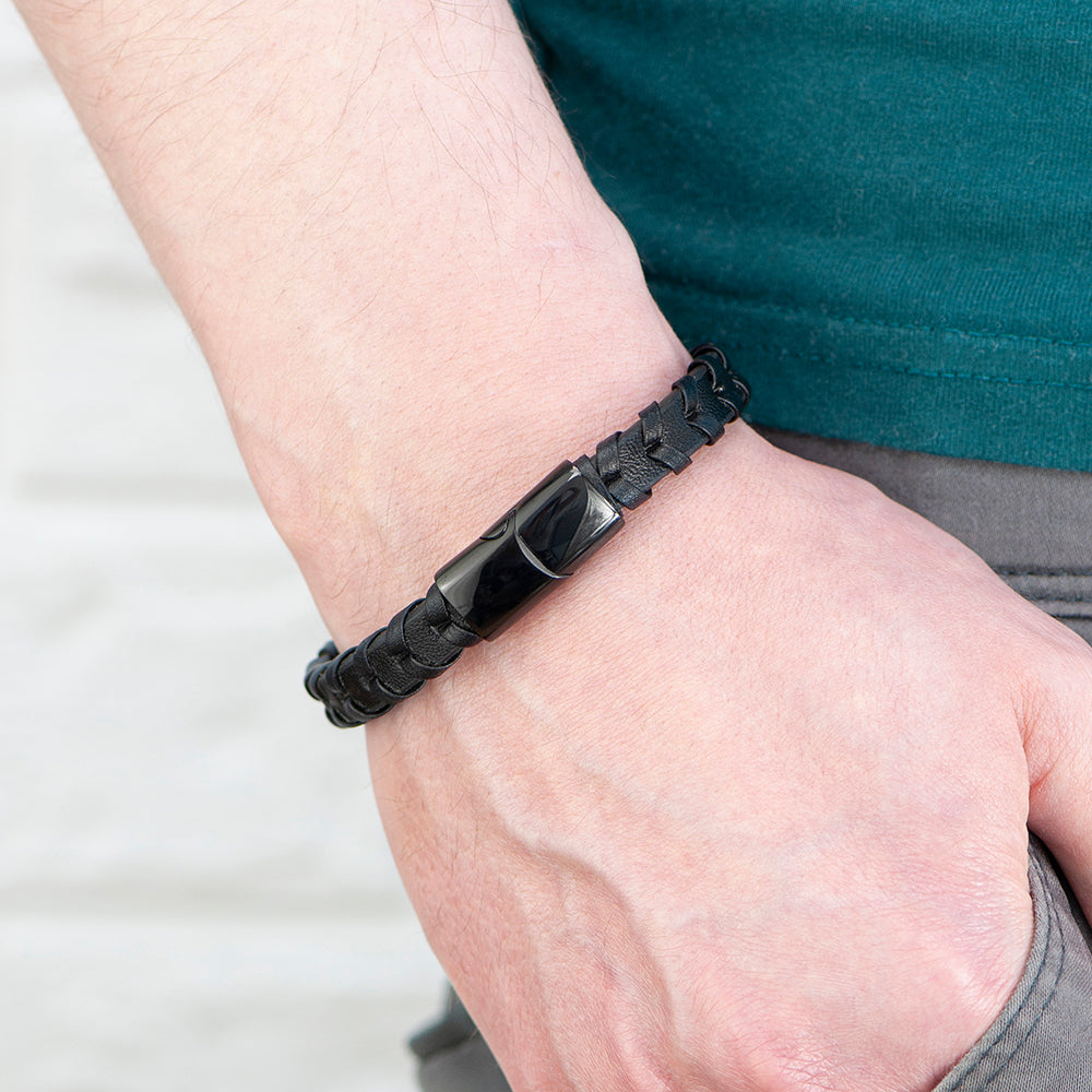 Black braided bracelet on a wrist with a blurred background