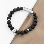 Black beaded bracelet with skull charm and engraved metal tag on wrist